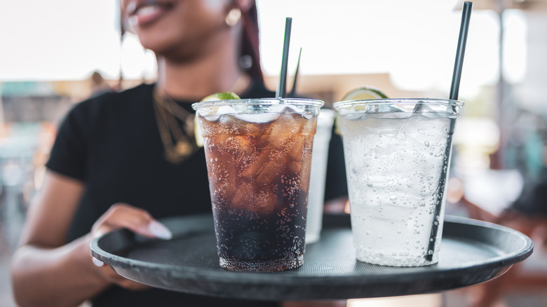 waitress holding tray with glasses of lemonade and coke