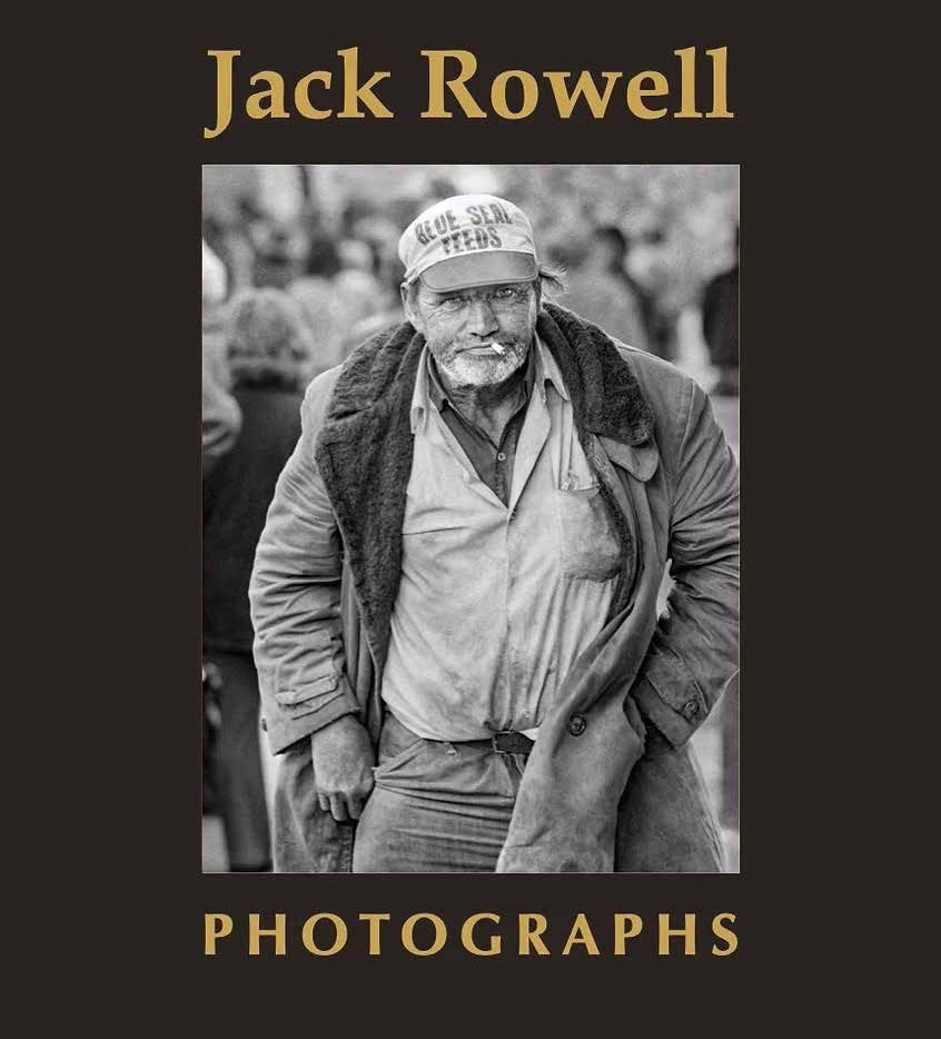 Black-and-white photo of an older man in rugged clothing and a cap, looking at the camera. Text above reads "Jack Rowell," and below reads "Photographs.