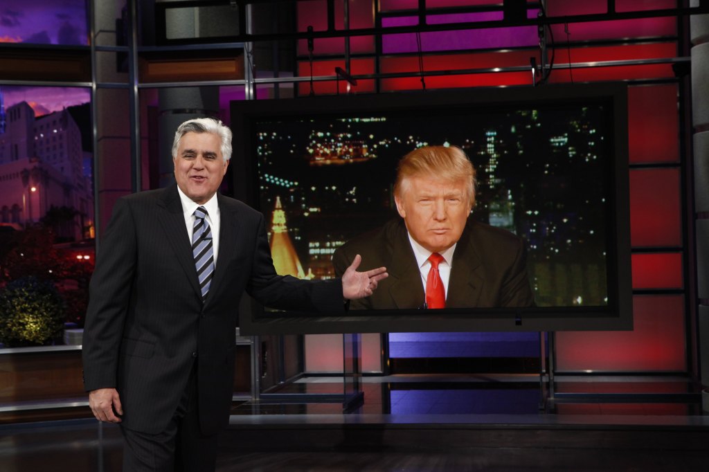 Jay Leno pointing at an image of Donald Trump on a large screen during "The Jay Leno Show".