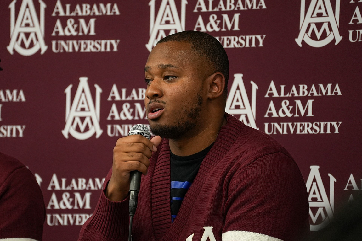 Brian Hill holds microphone while talking to AAMU students