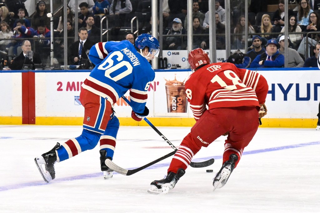 New York Rangers defenseman Scott Morrow (60) skates with the puck while defended by Detroit Red Wings center Andrew Copp (18).