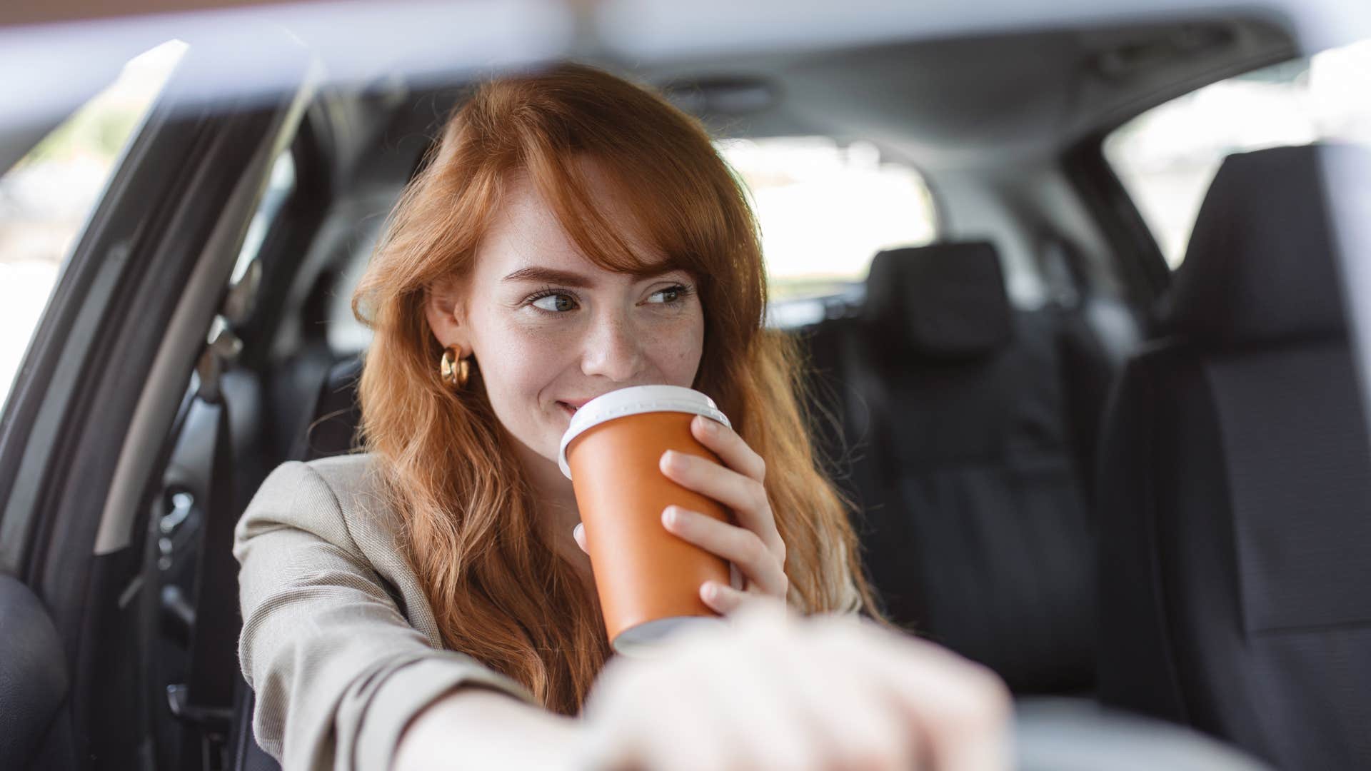 woman drinking energy drink in her car