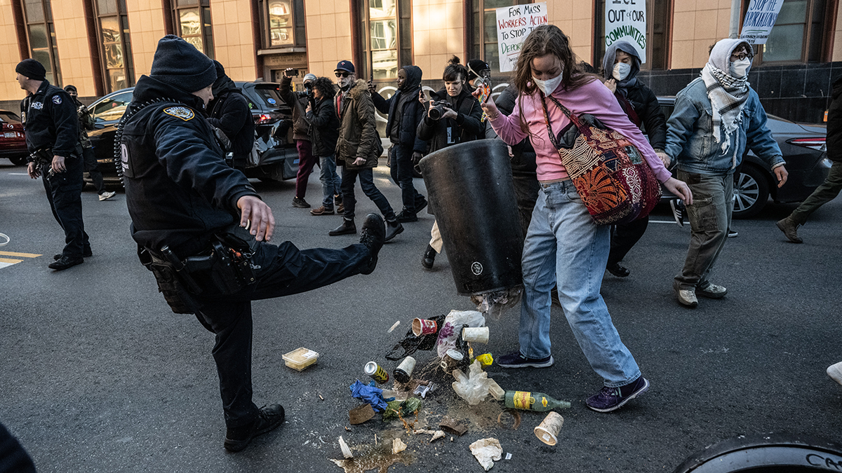An NYPD officer kicks trash out of the way during an anti-ICE riot in New York City on Saturday, Nov. 29, 2025.