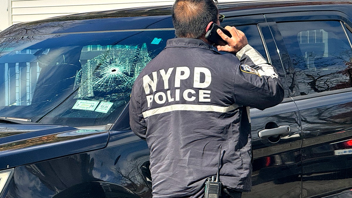 NYPD officer outside unmarked car with hole in windshield