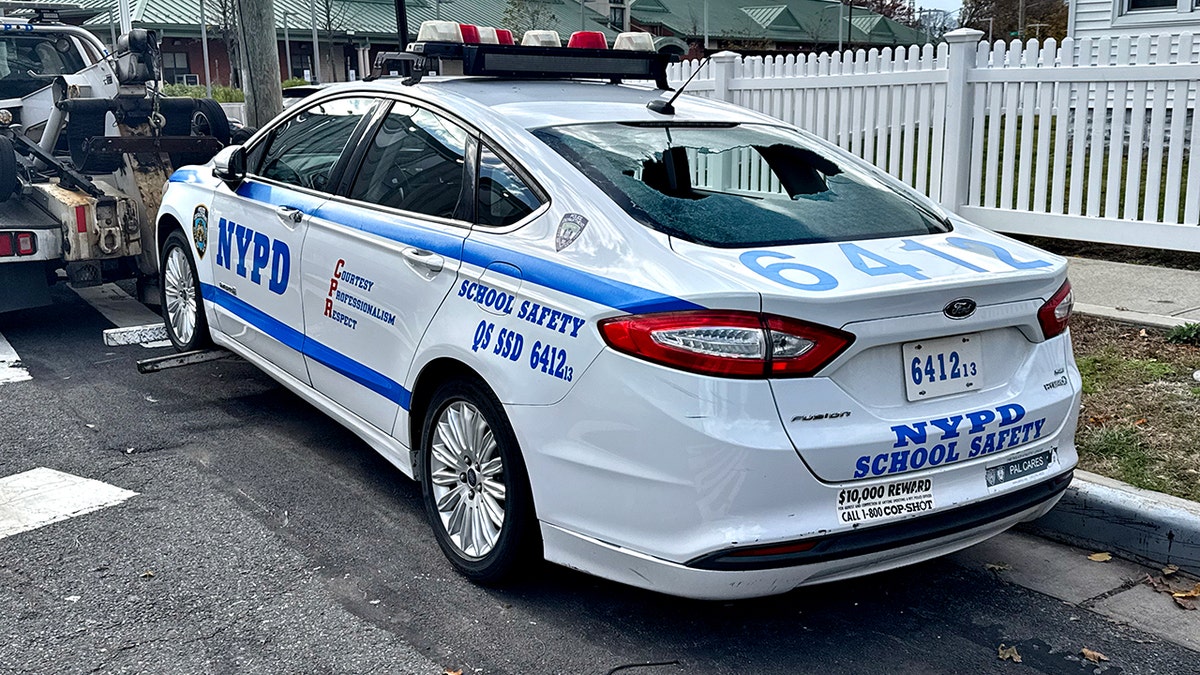 NYPD patrol car with broken back window being towed