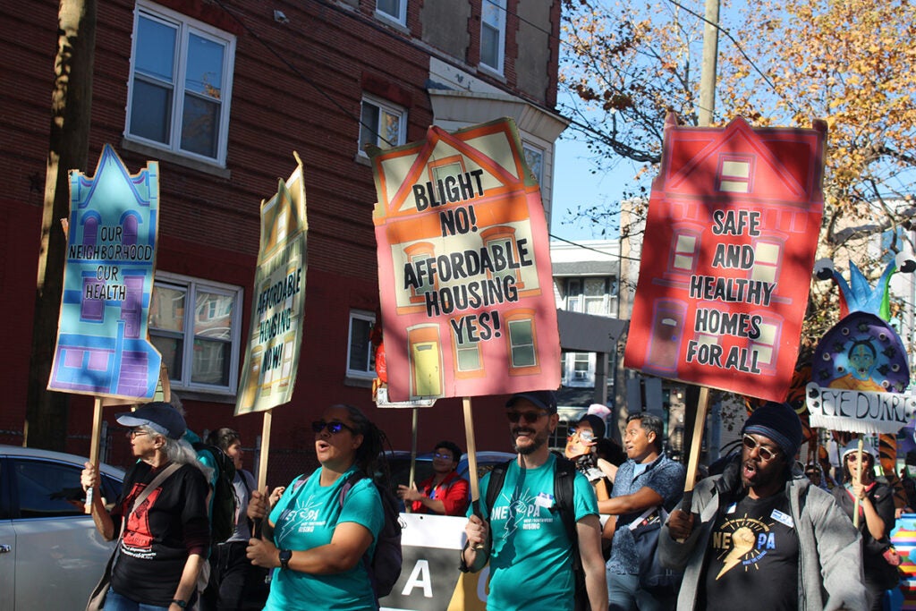 People hold signs advocating for affordable housing in the 25th annual Peoplehood Parade in West Philadelphia
