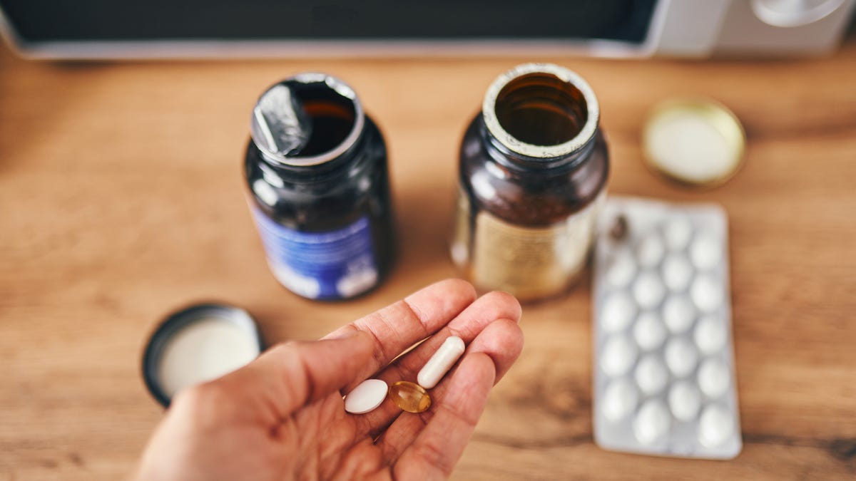 Pouring vitamins on one hand from a bottle