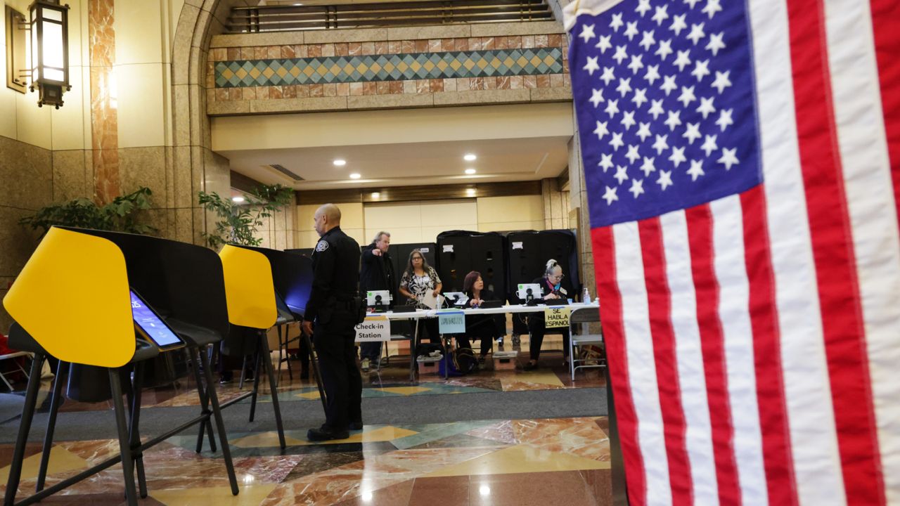 Workers wait for voters to arrive at a polling station on Tuesday in Los Angeles. (AP Photo/Ethan Swope)