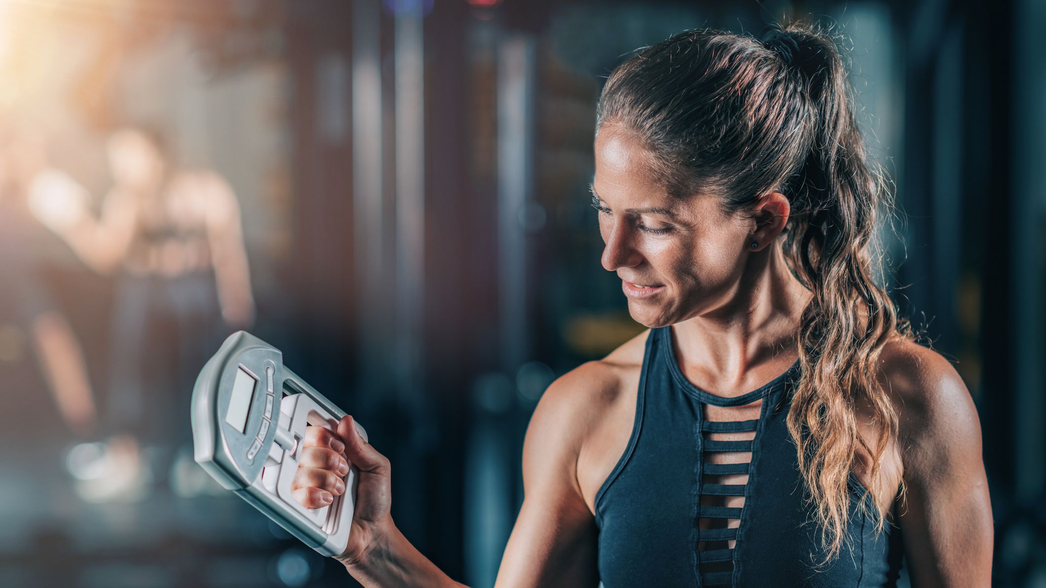 Woman in sportswear using dynamometer to test grip strength