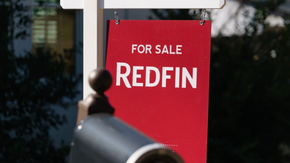 A Redfin sign in front of a home for sale.