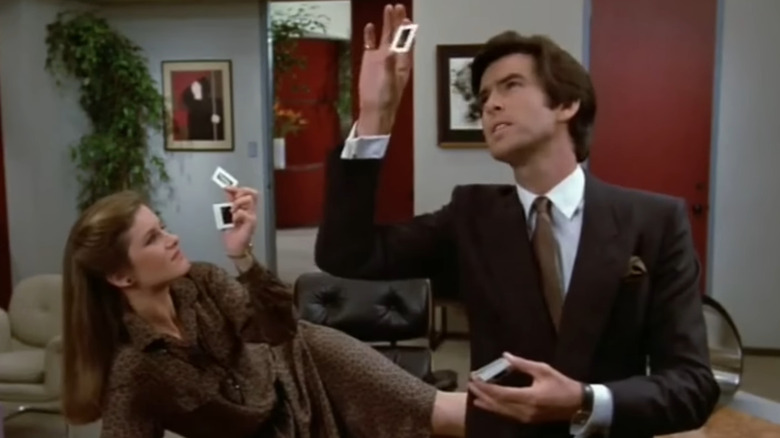 Stephanie Zimbalist's Laura Holt and Pierce Brosnan's Remington Steele looking at photos in Remington Steele