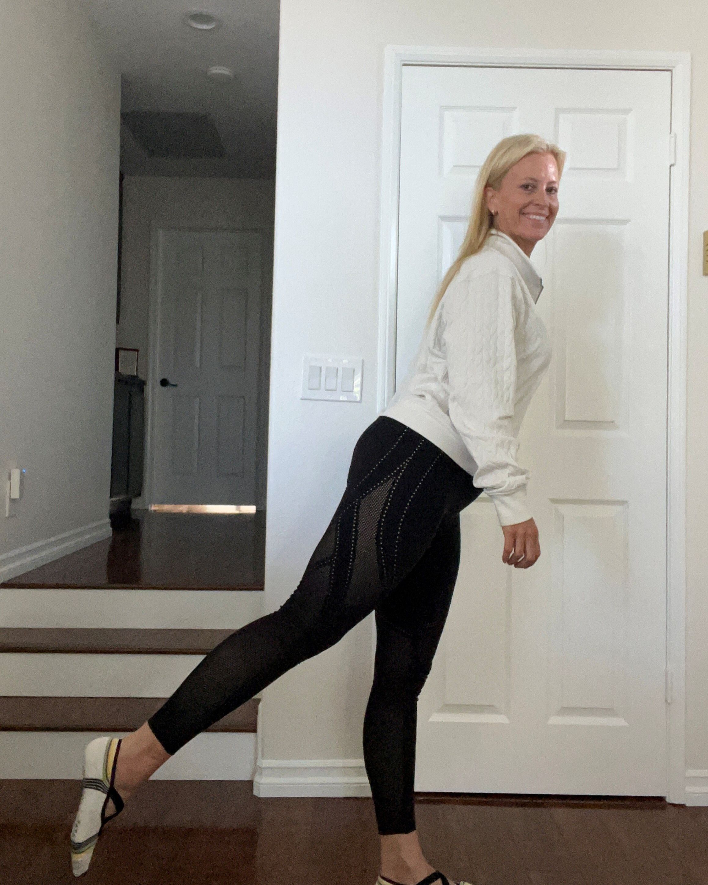 Woman standing on one leg with her raised foot behind her