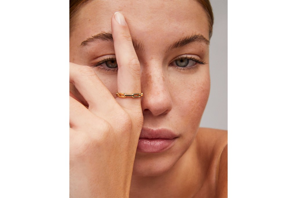Close-up of a model wearing a gold chain link ring on her middle finger.