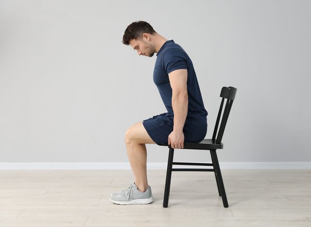 Handsome man exercising with chair at home