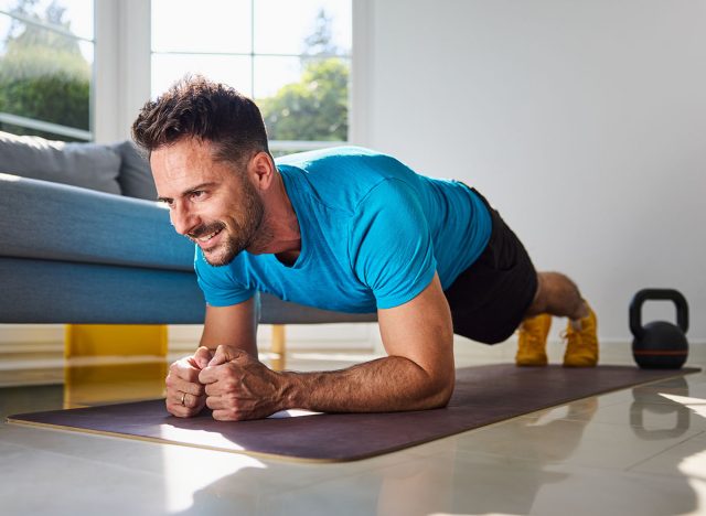 Smiling mid adult man doing plank exercise during home workout