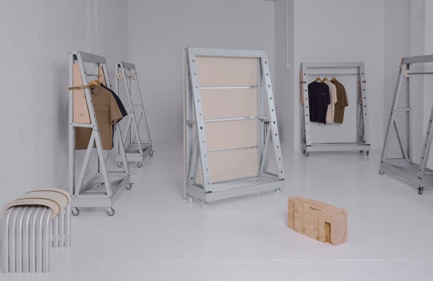 Minimalist industrial furniture installation featuring steel and wood modular frames on caster wheels in a white gallery space.