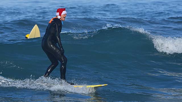 A member of the Bad Boys of Summer Surf Club dons a Santa hat for its weekly surfing session at La Jolla Shores Beach.