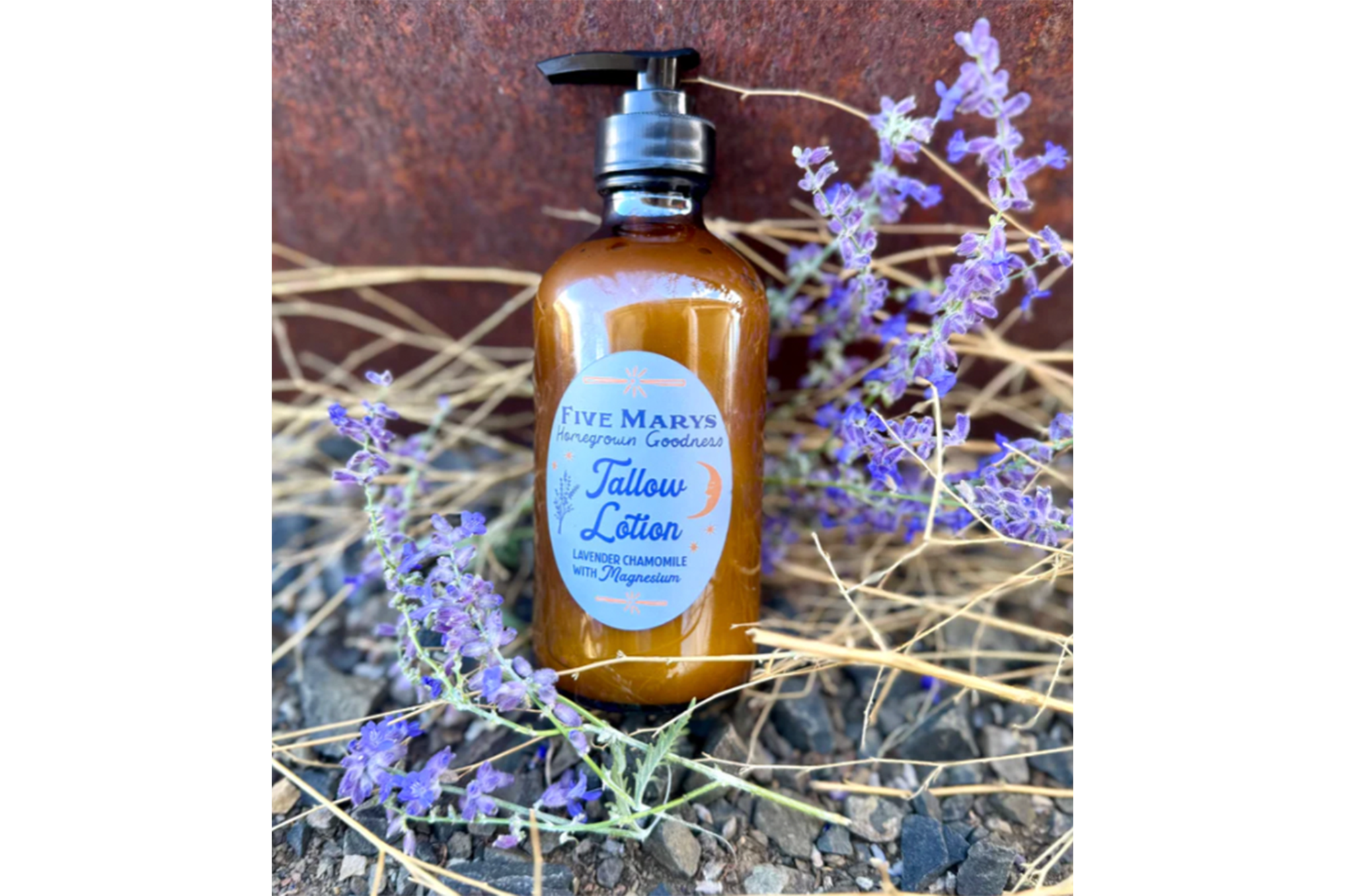 Brown pump bottle of "Five Marys Homegrown Goodness Tallow Lotion, Lavender Chamomile with Magnesium" among lavender flowers and dry grass.