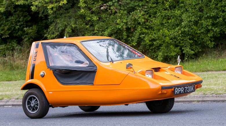 1972 Bond Bug in orange driving on English road.