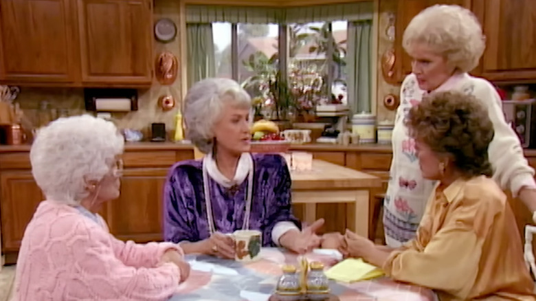 Bea Arthur's Dorothy Zbornak speaking to Betty White's Rose Nylund, Rue McClanahan's Blanche Devereaux, and Estelle Getty's Sophia Petrillo in The Golden Girls