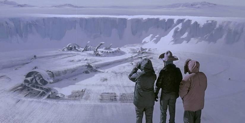 Three researchers look at a UFO buried in snow at a distance in The Thing (1982)