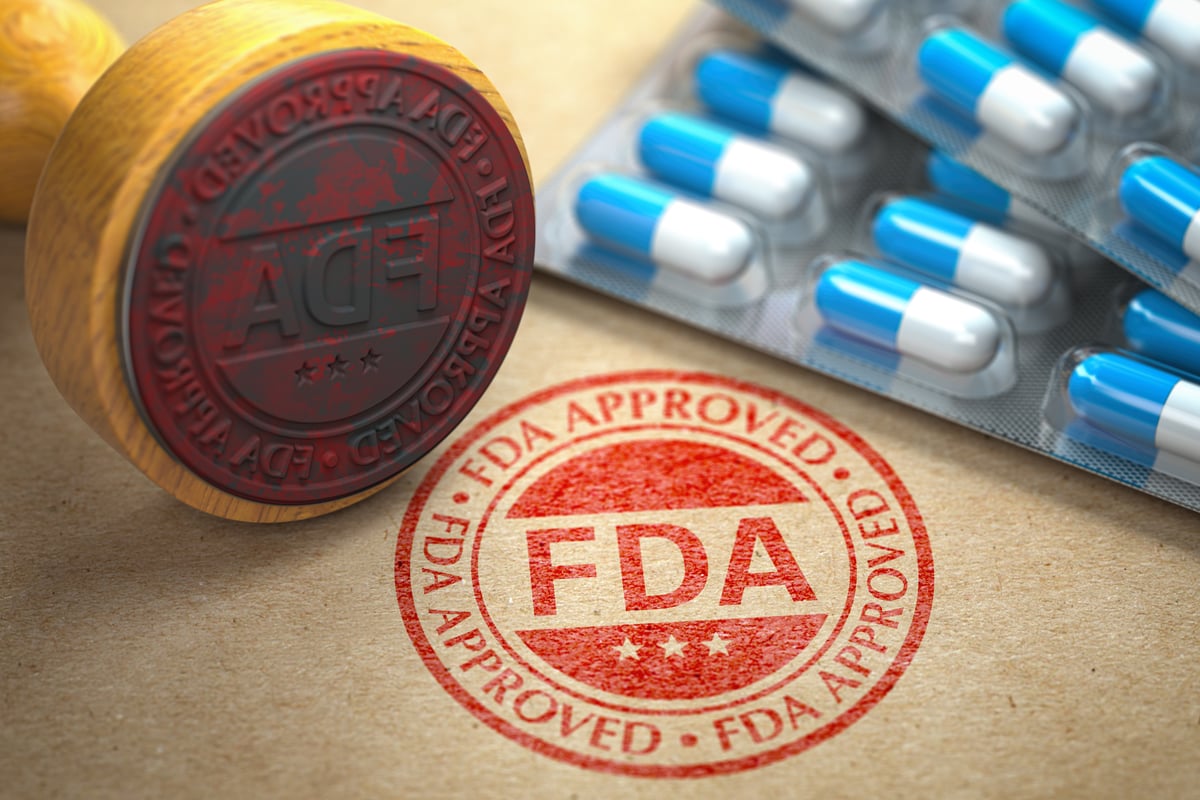 A rubber stamp that says FDA Approved next to some packages of pills.