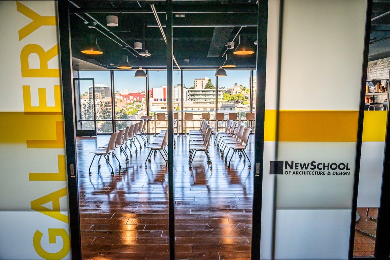 Chairs lined up on a bright new floor with windows looking out on the downtown landscape. On one side the door reads "gallery" and the other, NewSchool of Architecture & Design.