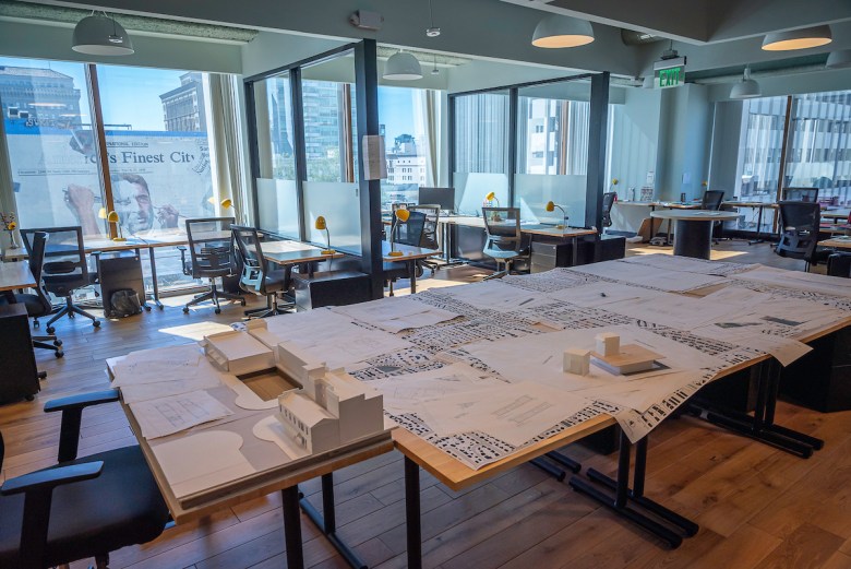 Drafting tables at the new campus for NewSchool of Architecture, with a flood of light from windows on a far wall overlooking a sign reading "America's Finest City." 