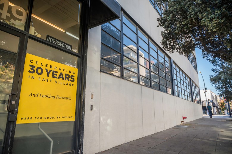 A large building with several windows sits deserted on a city street with a lone pedestrian walking by. It's the former NewSchool in downtown San Diego.