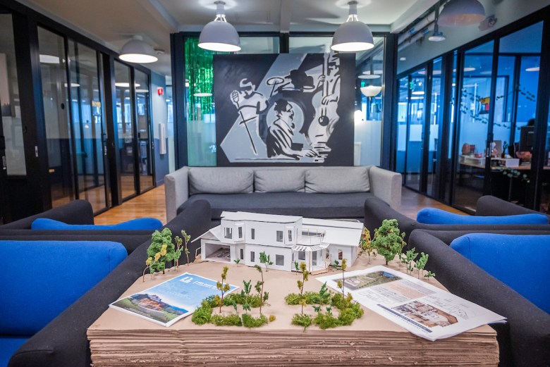 Modern artwork with a man on a black backround domniates a waiting area with cushioned seats between glassed-in rooms.