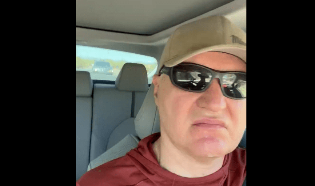 a man in a car wearing sunglasses and a hat