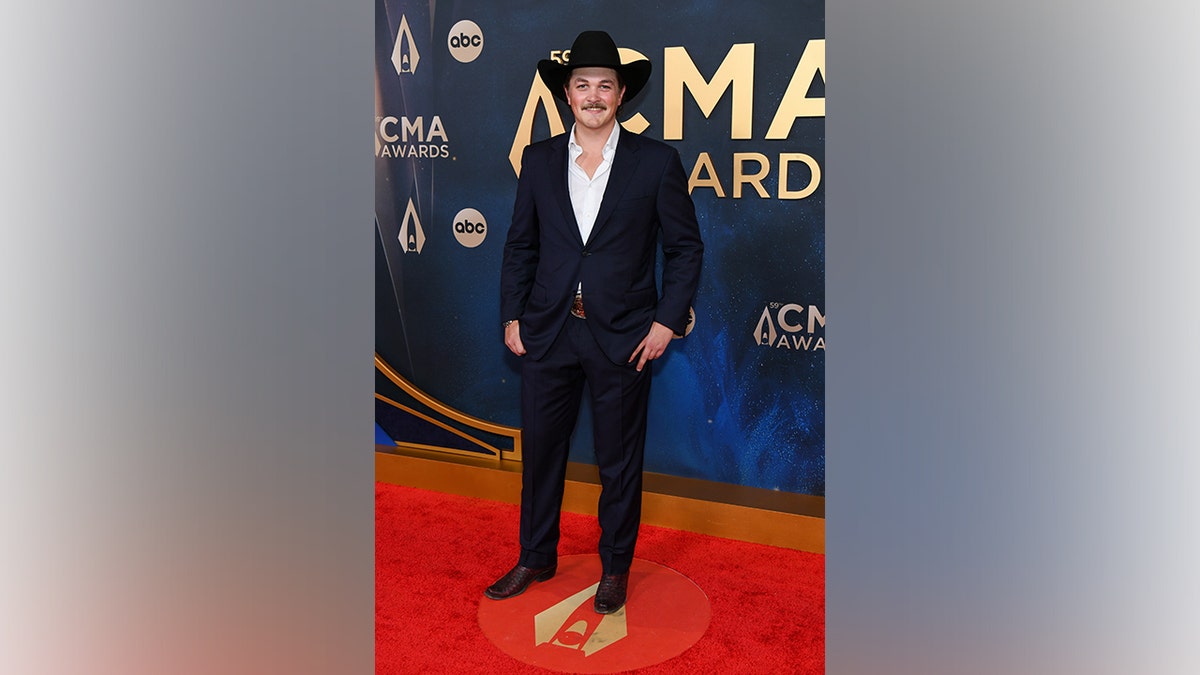 Country artist Zach Top poses on the red carpet wearing a navy suit, white shirt, cowboy hat, and boots at the 59th Annual CMA Awards in Nashville, Tennessee, on November 19, 2025.
