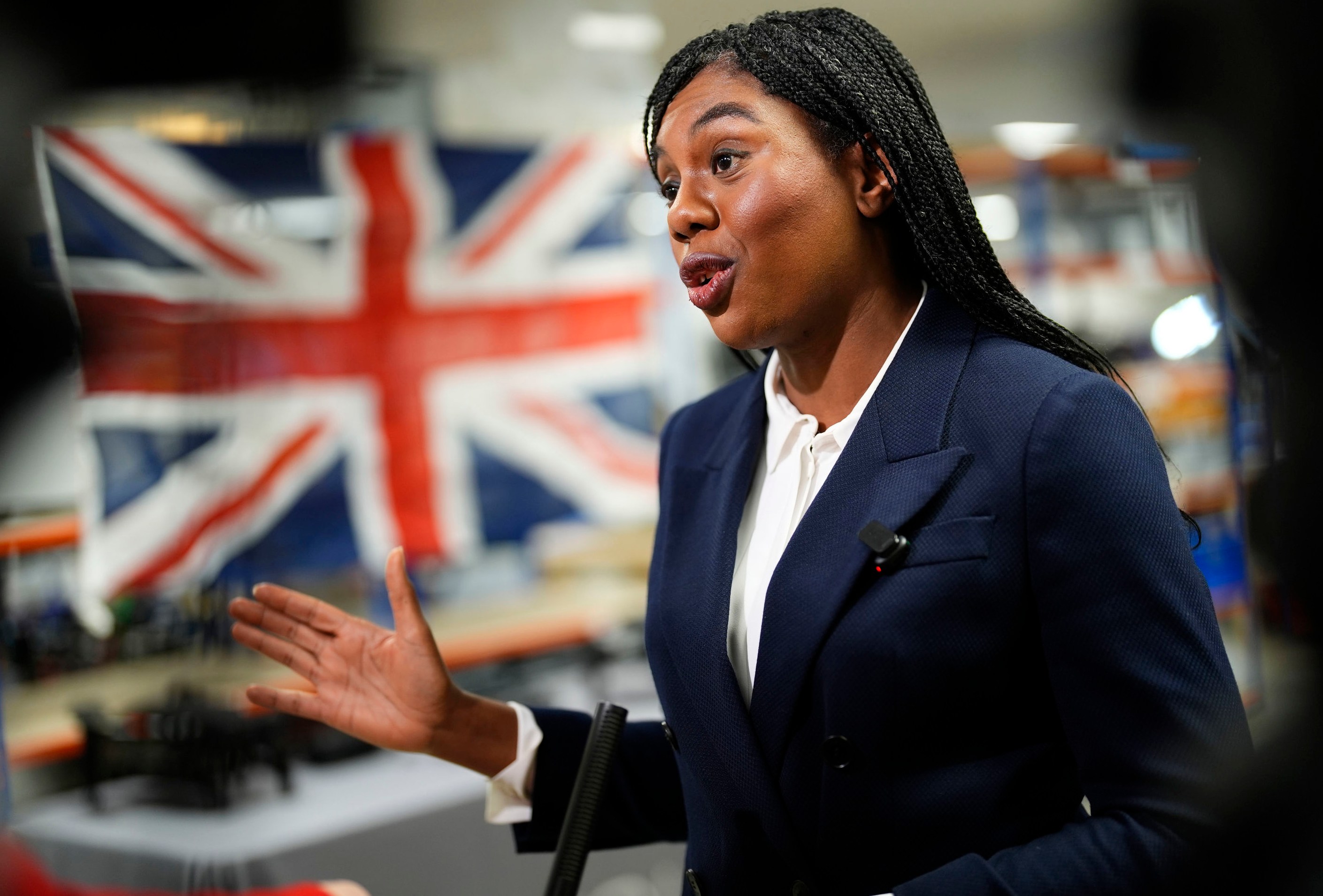 Conservative Party leader Kemi Badenoch speaking during a visit to Evolve Dynamics in Farnham, Hampshire, with a Union Jack flag in the background.