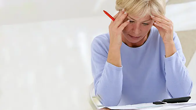 Confused woman sitting at home making calculations