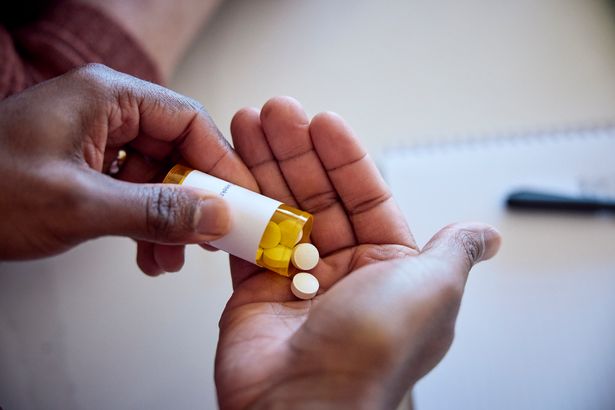 man pouring medications out of a bottle into his hand.
