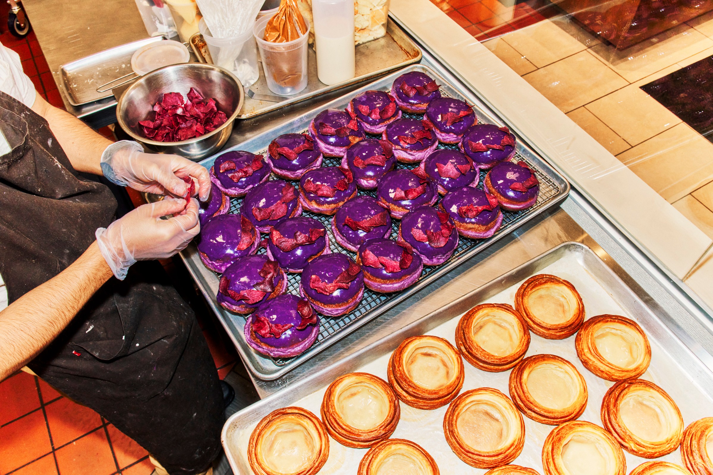Purple Ube brioche doughnuts are prepared on a baking sheets next to most pastries.