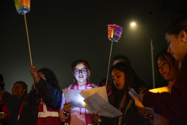 A group of people holding papers and a colorful lantern at an outdoor night event.
