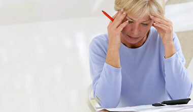 Confused woman sitting at home making calculations
