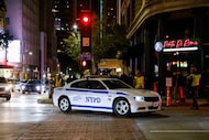 A New York Police Department vehicle drives off Ervay Street during filming for The Madison,...