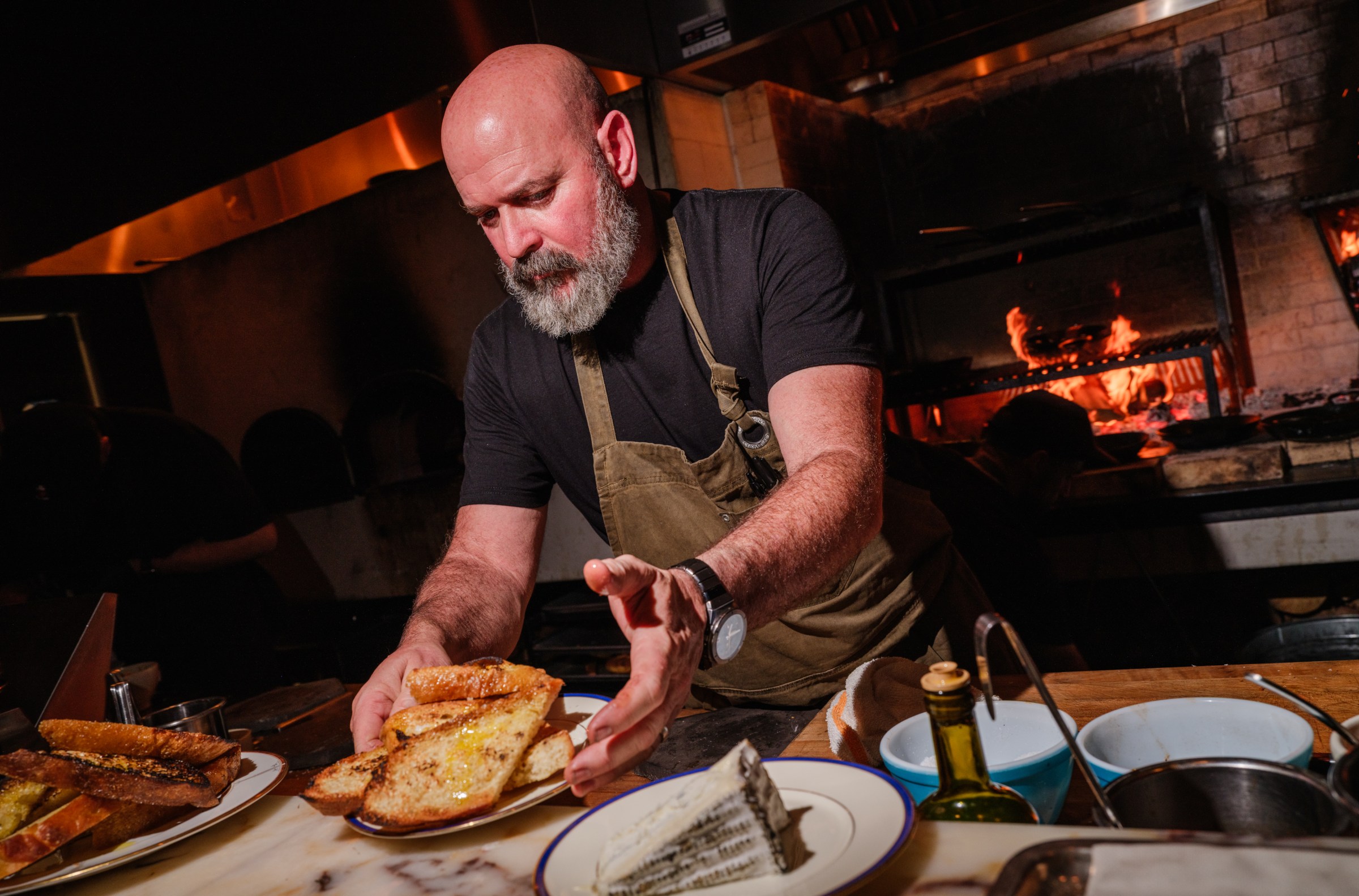 Chef Paul Downer passing a dish across a counter at Betsy.