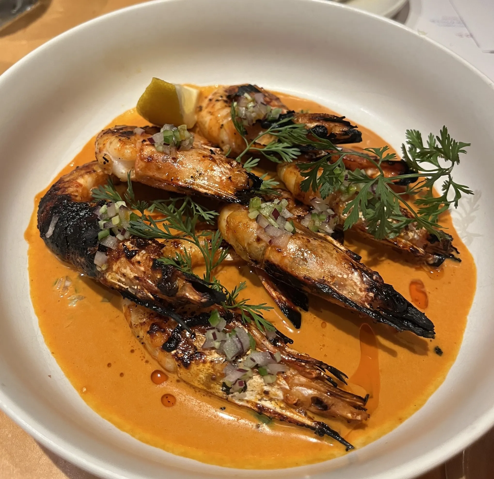 Charred prawns with herbs and mole oil on top