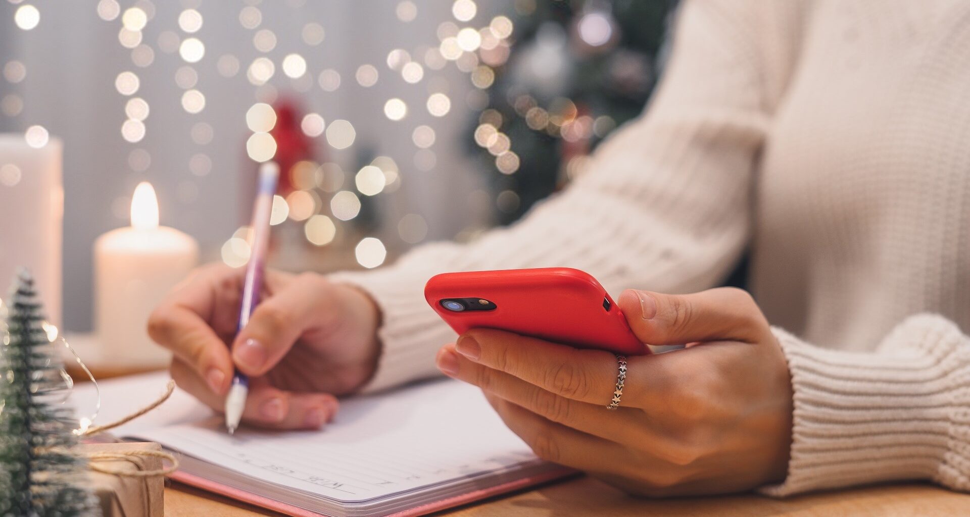 Woman hands with pen and mobile phone writing christmas wish list, goals. stock photo