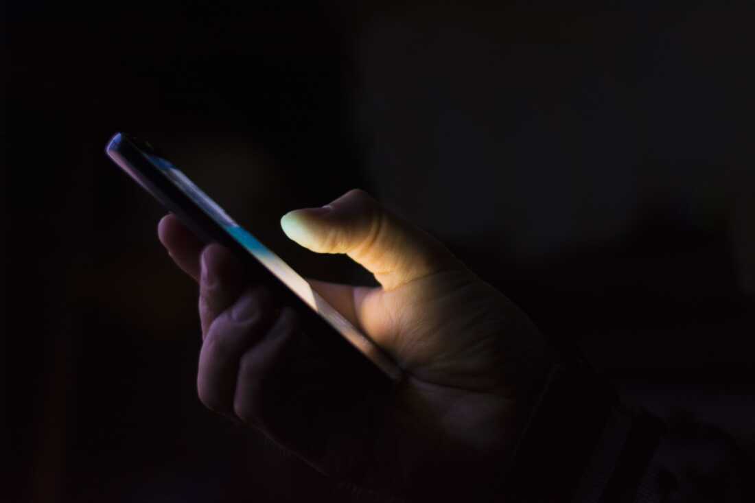 a hand holding a smart phone in the dark