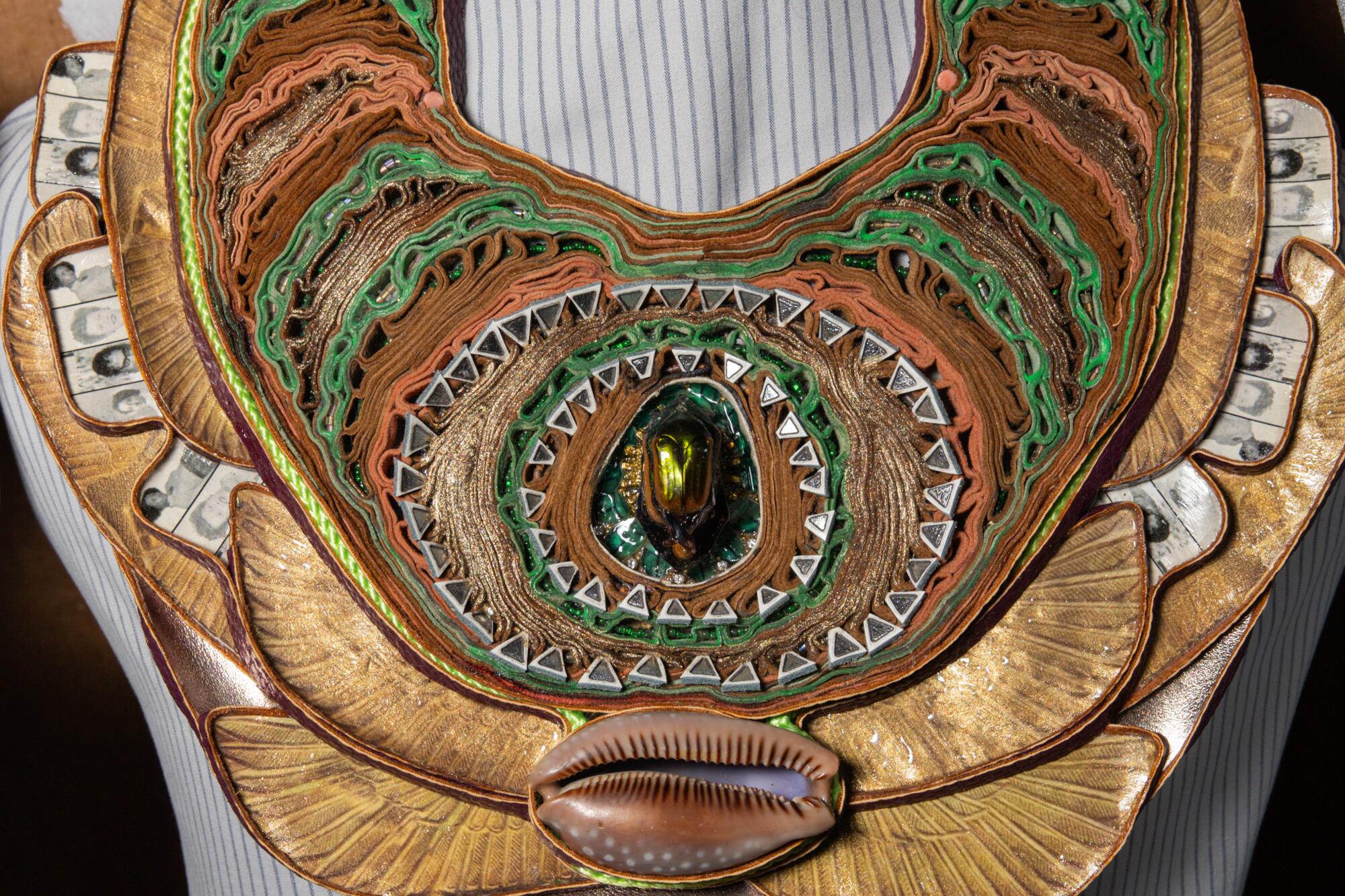 A large necklace with a cowrie shell and a pair of beetles.