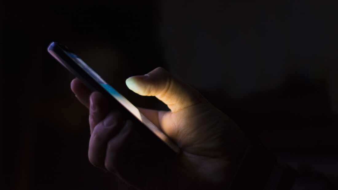 a hand holding a smart phone in the dark