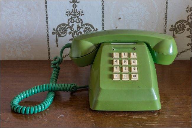 A vintage touch-tone telephone on a wooden table.