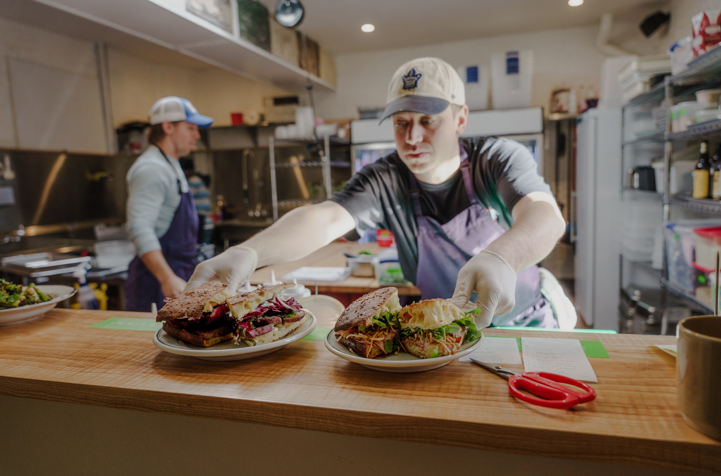 A kitchen staffer placing two dishes of food on a counter.