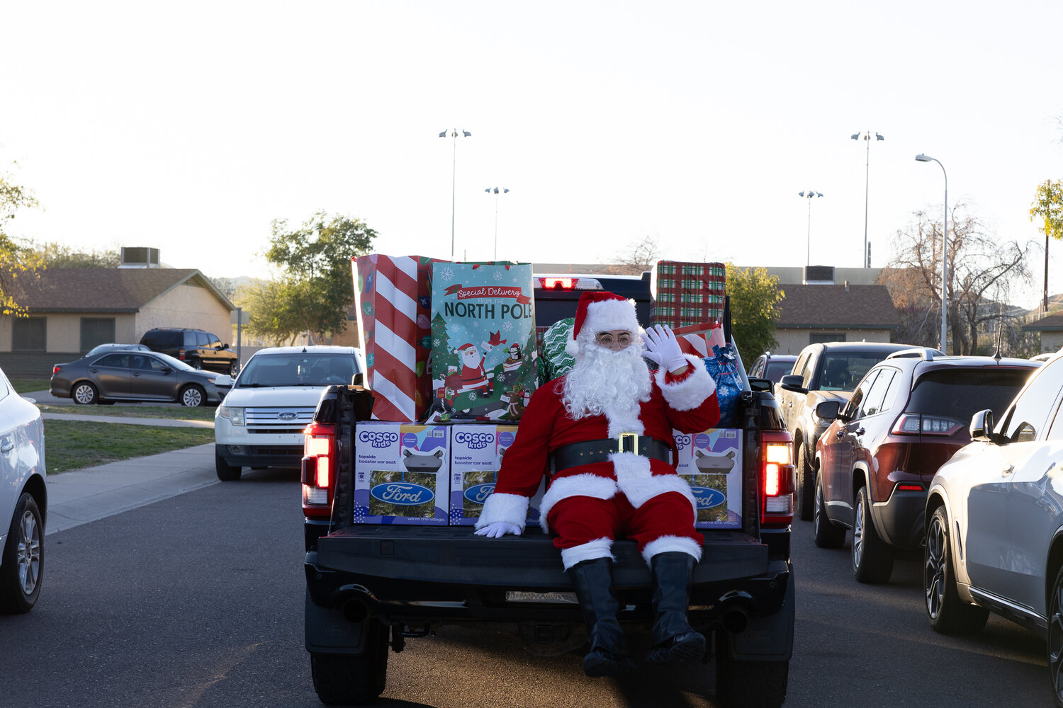 "Santa" sits on the bed of a pickup truck, with toys and gifts for Phoenix and Tempe families.