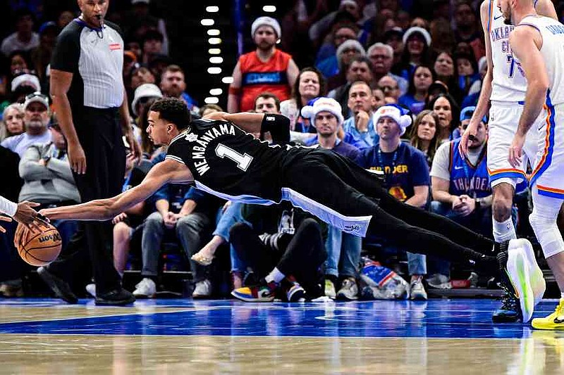 San Antonio Spurs forward/center Victor Wembanyama (1) goes for the free ball against the Oklahoma City Thunder during the second half of an NBA basketball game, Thursday, Dec. 25, 2025, in Oklahoma City. (AP Photo/Gerald Leong)