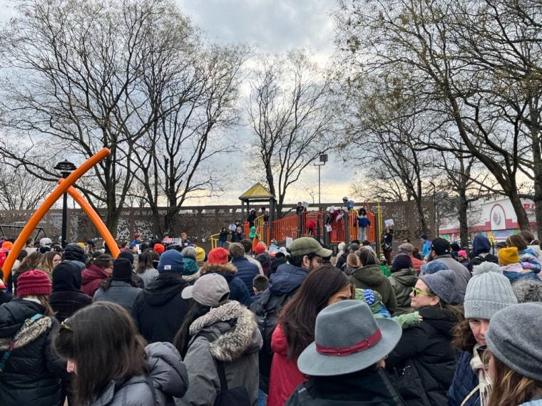 People gather outside at a playground for a protest